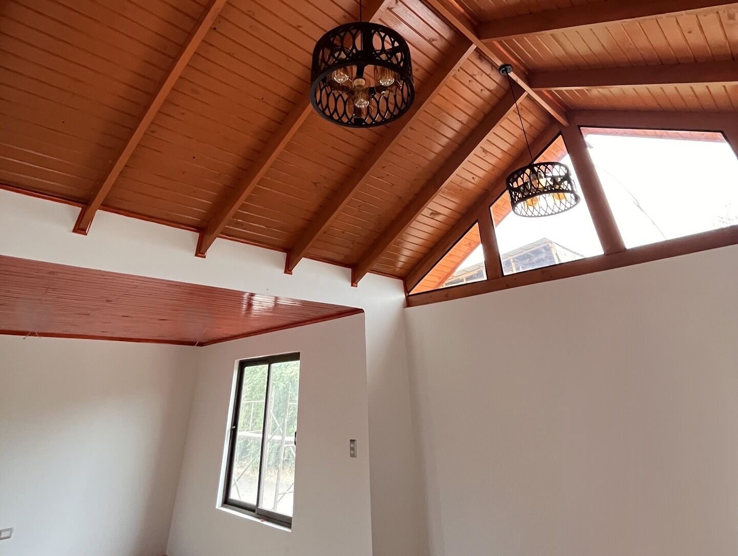Cielo de madera machihembrada barnizada con vigas a la vista en vivienda unifamiliar en Talca