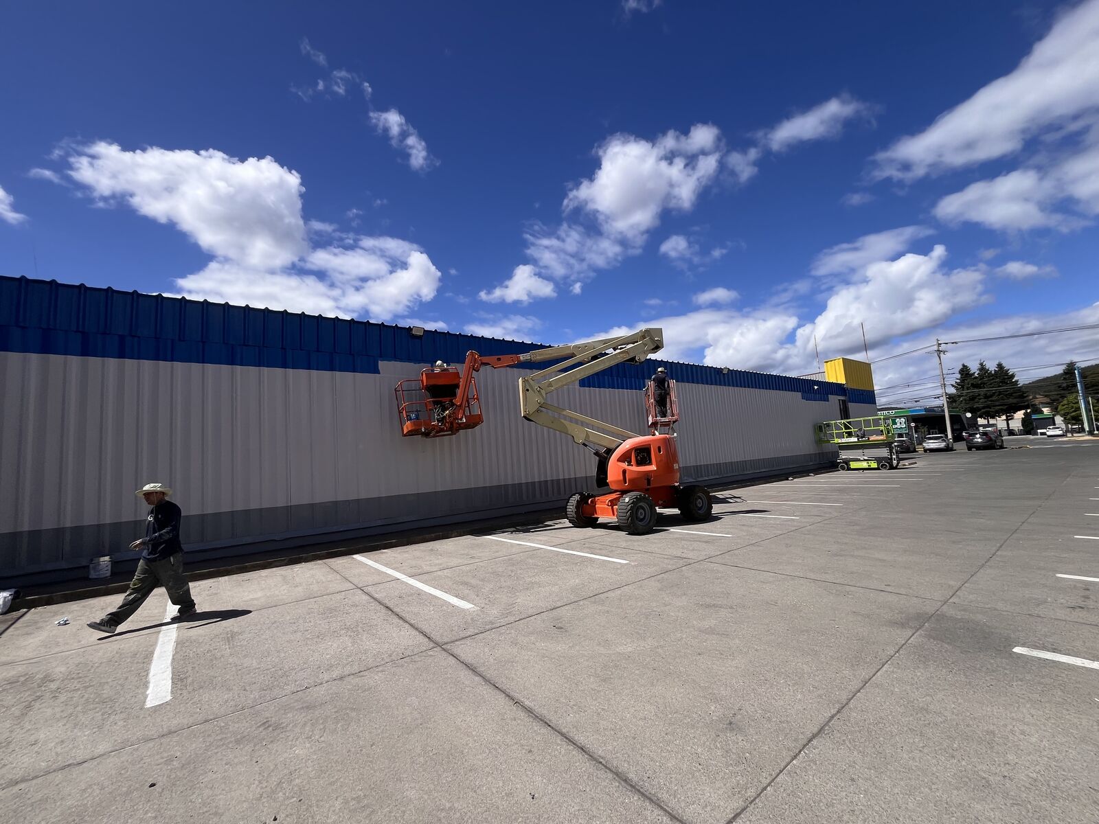 Pintura de revestimiento de fachada en altura con plataforma elevadora en supermercado Alvi Angol