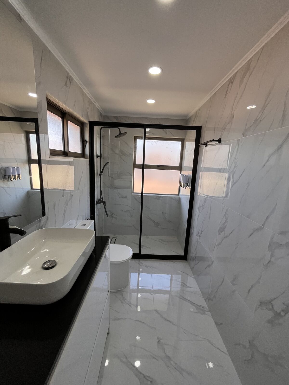 Remodelación completa de baño con revestimiento de mármol y ducha de vidrio en Talca