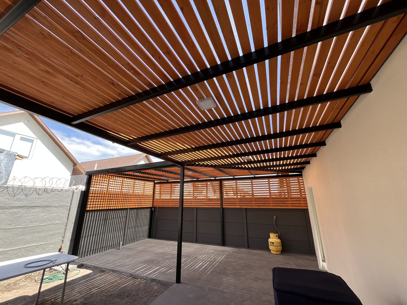 Terraza cubierta con estructura metálica y listones de madera ejecutada por GHM Civil