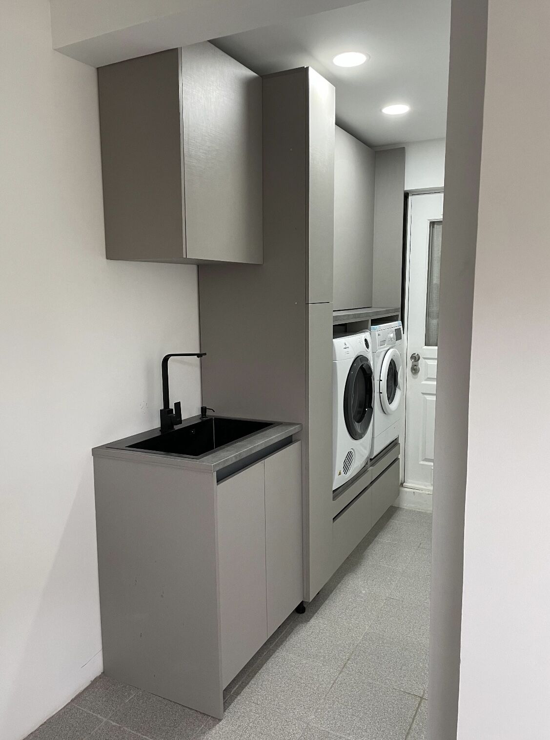 Zona de lavado remodelada con muebles grises, lavaplatos y closet en Talca